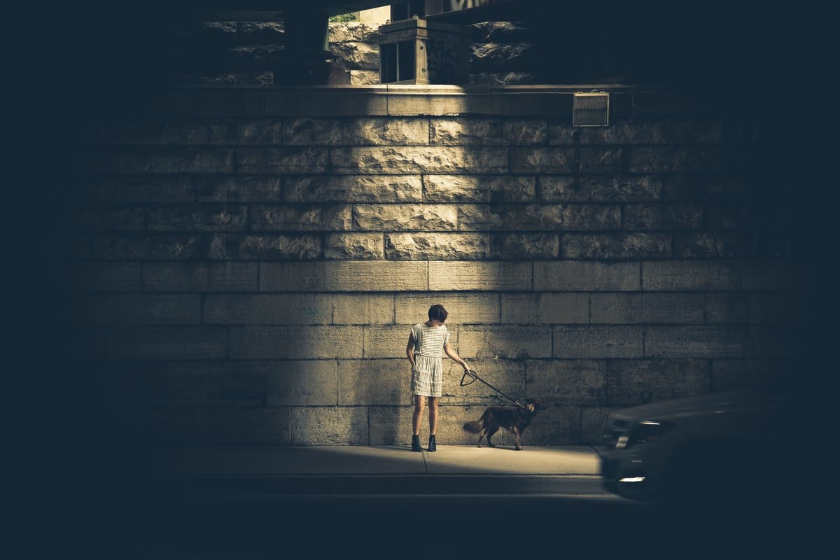 Frau mit Hund im Licht einer Straßenlaterne