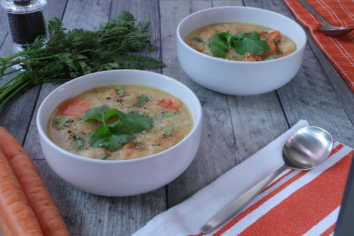 Schalen mit Gemüsesuppe und frischen Karotten