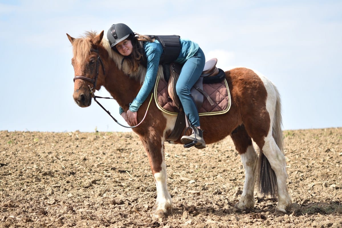 Reiterin umarmt ihr geschecktes Pony vom Sattel aus